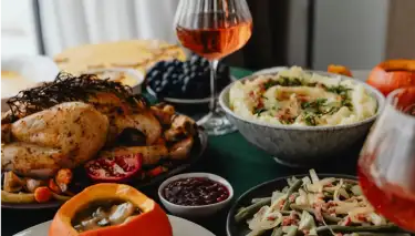 Table with Thanksgiving dinner (thurkey, mashed potatoes, salad) and glasses of wine