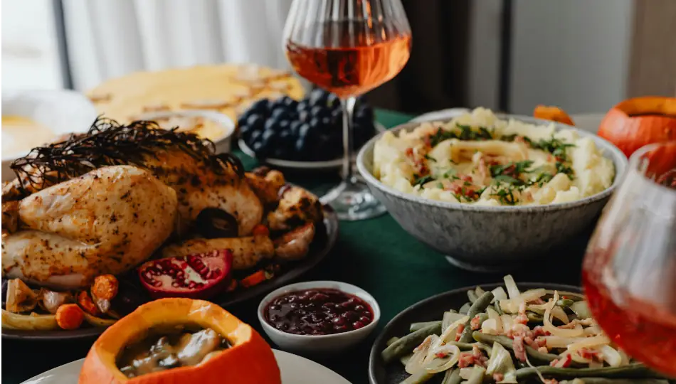 Table with Thanksgiving dinner (thurkey, mashed potatoes, salad) and glasses of wine